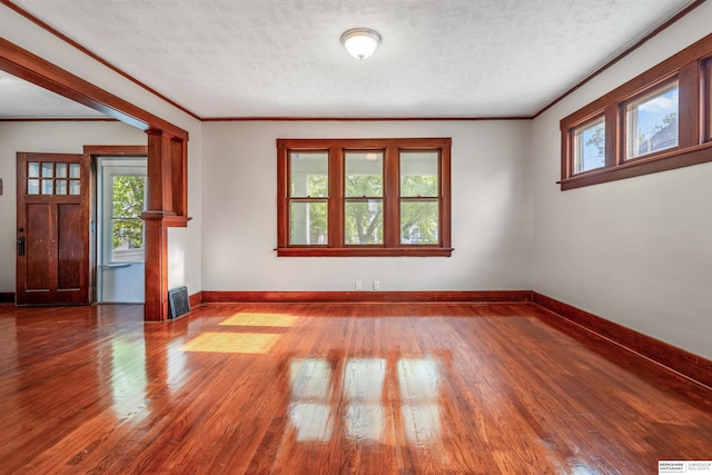 620 Dorcas St, Omaha, NE 68108 - empty room featuring hardwood / wood-style flooring, decorative columns, baseboards, ornamental molding, and a textured ceiling