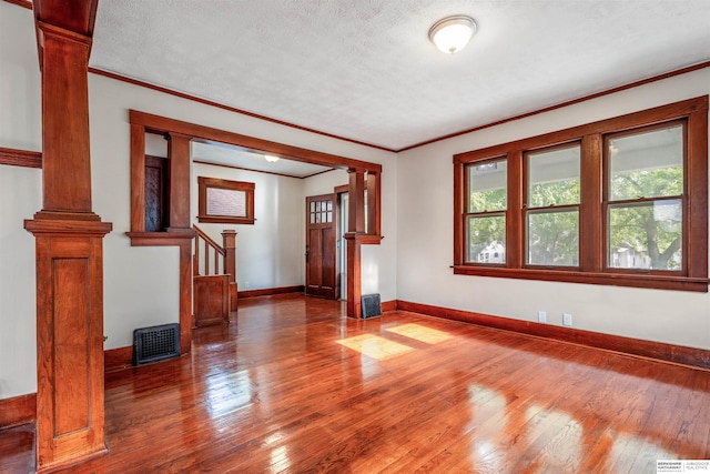 620 Dorcas St, Omaha, NE 68108 - empty room featuring ornate columns, ornamental molding, hardwood / wood-style flooring, baseboards, and a textured ceiling