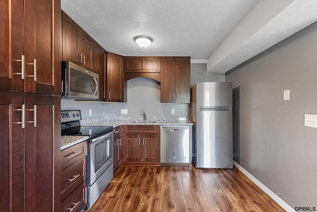 12749 Woodcrest Plz Unit 211B, Omaha, NE 68137 - kitchen with appliances with stainless steel finishes, a sink, dark wood-type flooring, and light stone counters