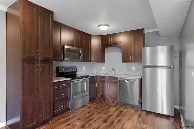 12749 Woodcrest Plz Unit 211B, Omaha, NE 68137 - kitchen featuring appliances with stainless steel finishes, dark wood finished floors, light stone countertops, a textured ceiling, and dark brown cabinetry