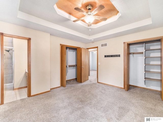 7824 La Vista Dr, La Vista, NE 68128 - unfurnished bedroom with a tray ceiling, light colored carpet, two closets, and ceiling fan