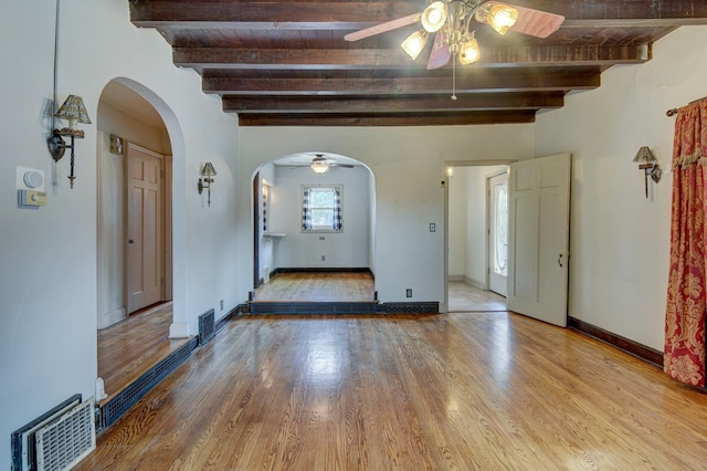 902 S 57th St, Omaha, NE 68106 - unfurnished room featuring ceiling fan, arched walkways, wood finished floors, and a wood ceiling with exposed beams