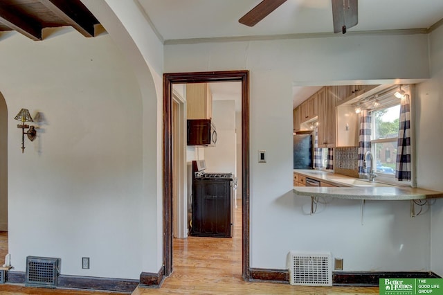 902 S 57th St, Omaha, NE 68106 - kitchen featuring arched walkways, gas stove, stainless steel microwave, ceiling fan, and light wood-style flooring