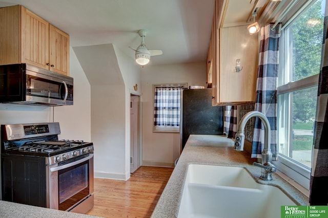 902 S 57th St, Omaha, NE 68106 - kitchen featuring appliances with stainless steel finishes, light brown cabinets, light wood finished floors, light countertops, and ceiling fan