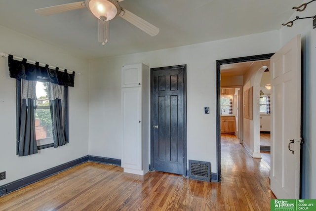 902 S 57th St, Omaha, NE 68106 - unfurnished bedroom featuring arched walkways, wood finished floors, and a ceiling fan