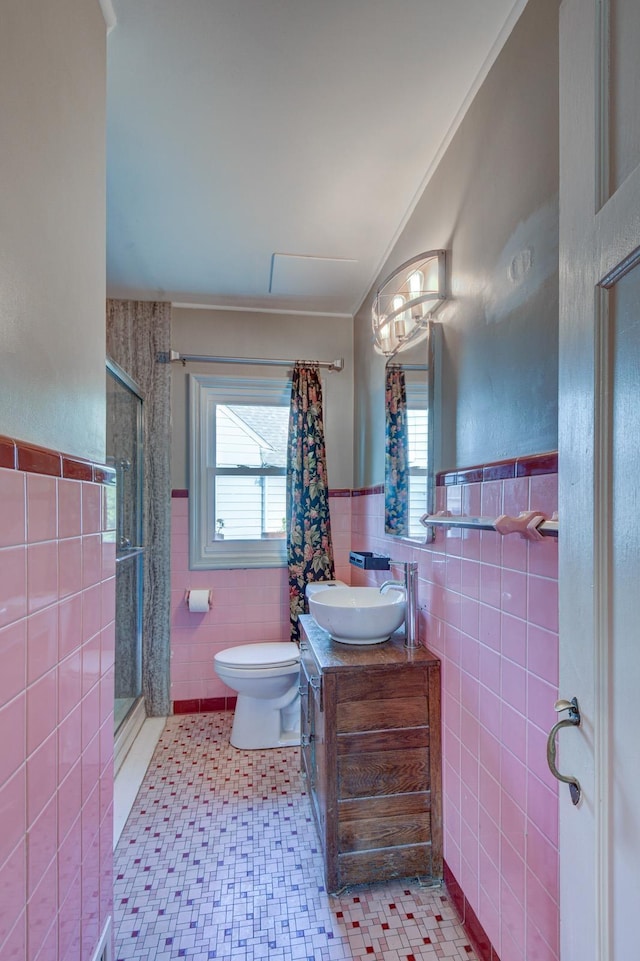 902 S 57th St, Omaha, NE 68106 - full bath featuring tile walls, a stall shower, plenty of natural light, vanity, and wainscoting