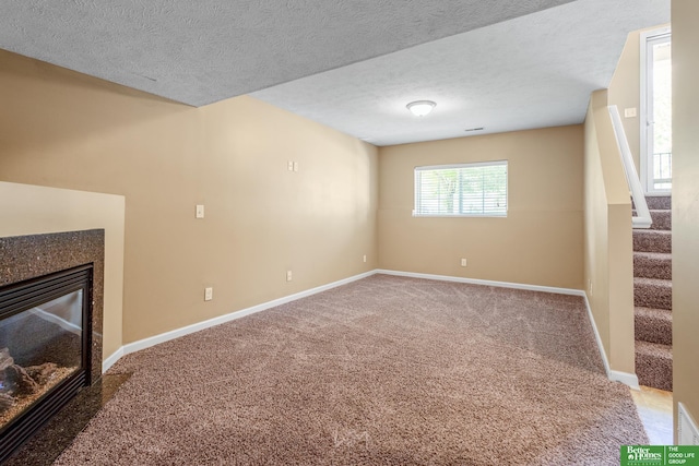 14463 Reynolds St, Omaha, NE 68007 - unfurnished living room with carpet, stairway, a glass covered fireplace, and a textured ceiling