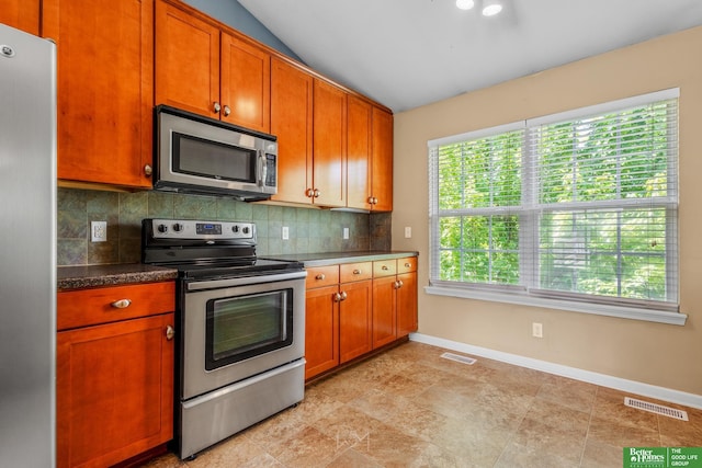 14463 Reynolds St, Omaha, NE 68007 - kitchen with appliances with stainless steel finishes, decorative backsplash, vaulted ceiling, brown cabinetry, and dark countertops