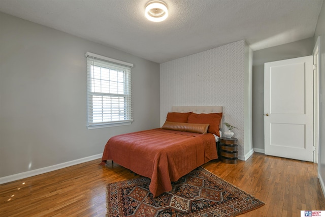 920 Clark Ave, Lincoln, NE 68510 - bedroom with baseboards, wood finished floors, an accent wall, and a textured ceiling