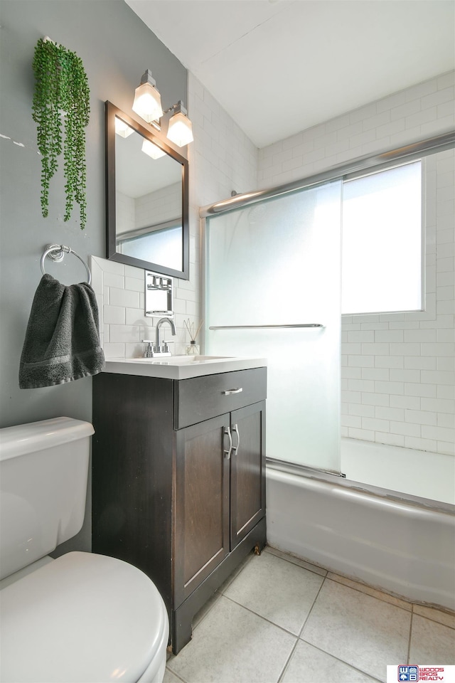 920 Clark Ave, Lincoln, NE 68510 - bathroom featuring toilet, tile patterned floors, vanity, enclosed tub / shower combo, and backsplash