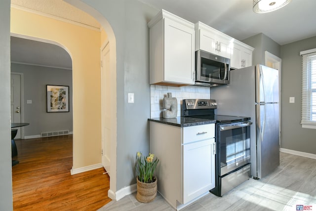 920 Clark Ave, Lincoln, NE 68510 - kitchen featuring stainless steel appliances, arched walkways, white cabinetry, tasteful backsplash, and light wood finished floors
