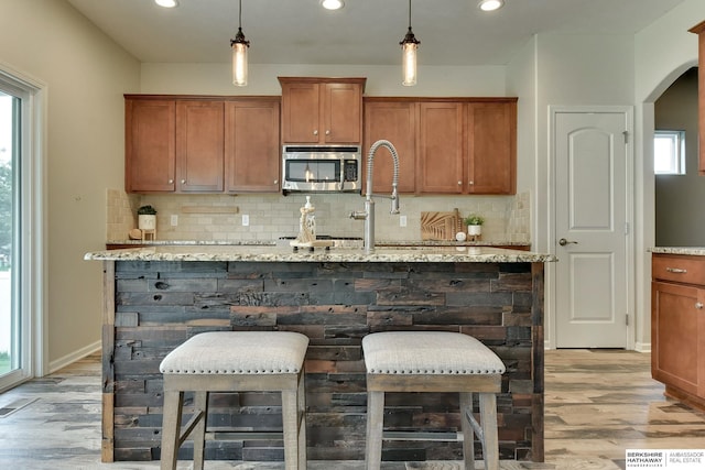 18337 Polk St, Omaha, NE 68135 - kitchen with stainless steel microwave, tasteful backsplash, light wood finished floors, brown cabinetry, and recessed lighting