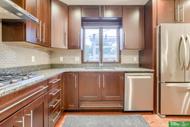 1008 J E George Blvd, Omaha, NE 68132 - kitchen featuring appliances with stainless steel finishes, wall chimney range hood, light wood-type flooring, a sink, and decorative backsplash