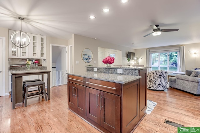 1008 J E George Blvd, Omaha, NE 68132 - kitchen featuring open floor plan, white cabinetry, light stone counters, glass insert cabinets, and decorative light fixtures