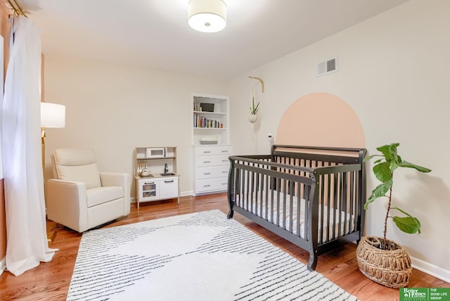 1008 J E George Blvd, Omaha, NE 68132 - bedroom featuring wood finished floors, a crib, and baseboards