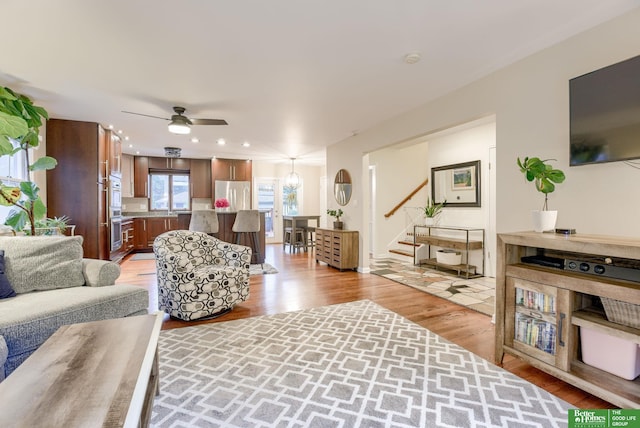1008 J E George Blvd, Omaha, NE 68132 - living room featuring light wood-style flooring, ceiling fan, and stairs
