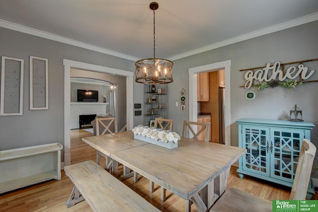 406 S 49th St, Omaha, NE 68132 - dining room featuring a fireplace, a chandelier, light wood-type flooring, ornamental molding, and arched walkways