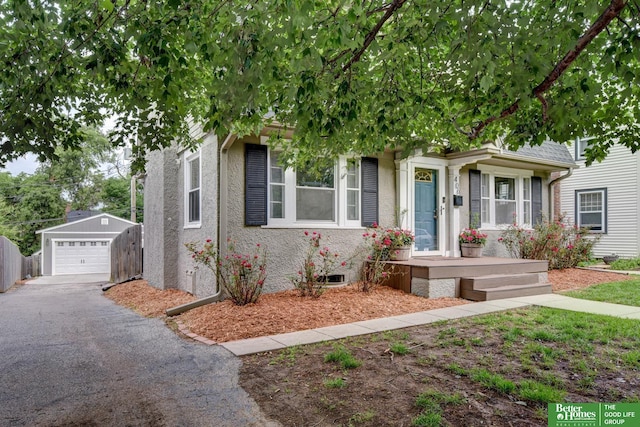 406 S 49th St, Omaha, NE 68132 - view of property hidden behind natural elements featuring a detached garage, asphalt driveway, an outdoor structure, and stucco siding
