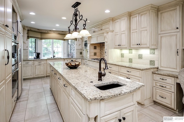 12829 Izard St, Omaha, NE 68154 - kitchen with a sink, cream cabinets, an island with sink, a peninsula, and recessed lighting
