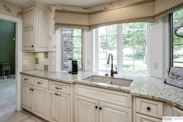 12829 Izard St, Omaha, NE 68154 - kitchen featuring a sink, light stone counters, plenty of natural light, and decorative backsplash