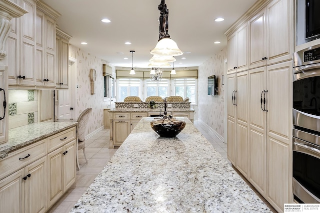 12829 Izard St, Omaha, NE 68154 - kitchen with cream cabinetry, baseboards, recessed lighting, wallpapered walls, and light stone countertops