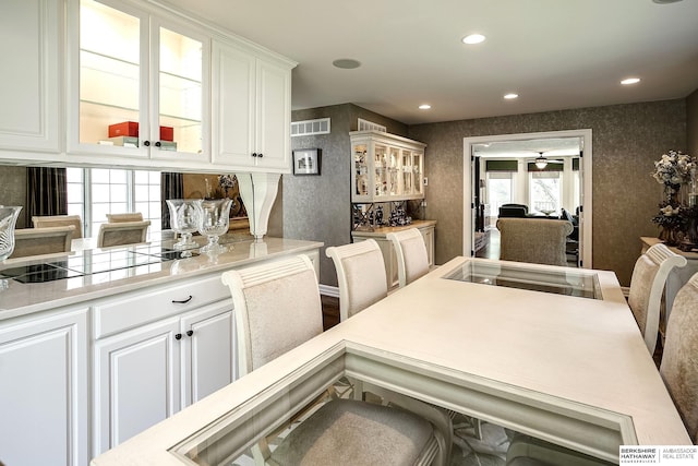 12829 Izard St, Omaha, NE 68154 - kitchen with black electric stovetop, glass insert cabinets, white cabinets, light countertops, and recessed lighting