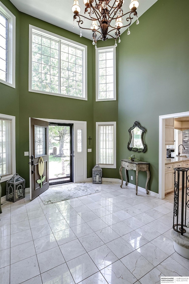 12829 Izard St, Omaha, NE 68154 - entrance foyer with a high ceiling, light marble finish floors, a chandelier, and baseboards
