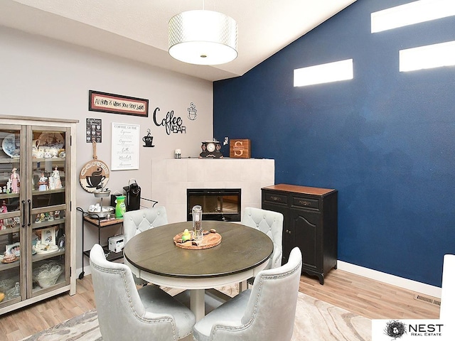 7615 Greycliff Dr, Lincoln, NE 68516 - dining space featuring light wood-style flooring, a tile fireplace, baseboards, and vaulted ceiling