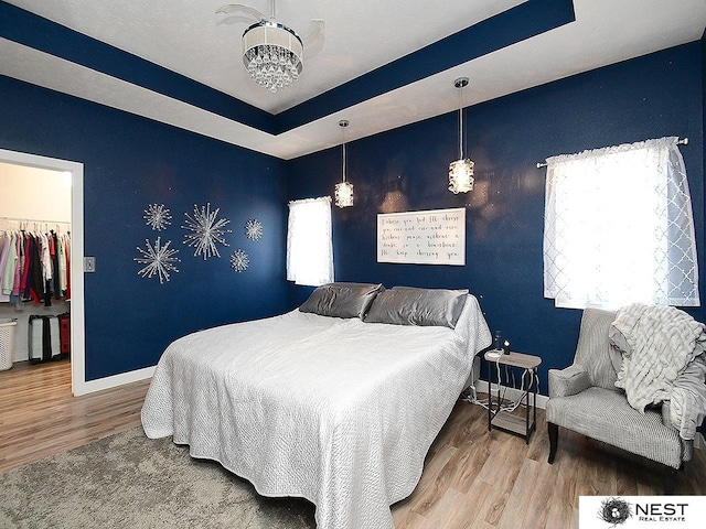 7615 Greycliff Dr, Lincoln, NE 68516 - bedroom featuring baseboards, wood finished floors, a walk in closet, a chandelier, and a closet