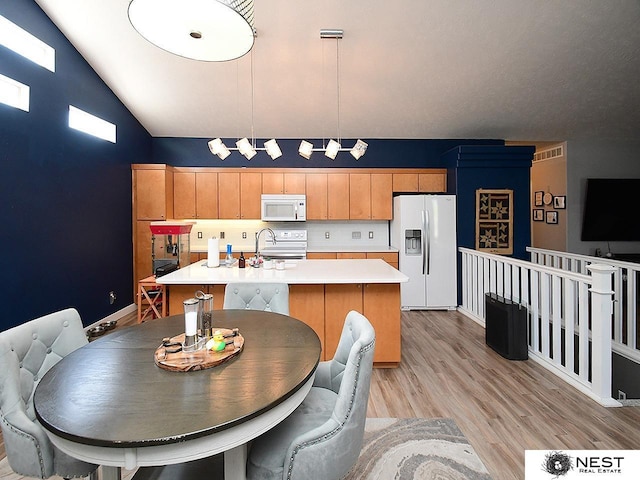 7615 Greycliff Dr, Lincoln, NE 68516 - kitchen featuring white appliances, light countertops, an island with sink, light wood finished floors, and vaulted ceiling