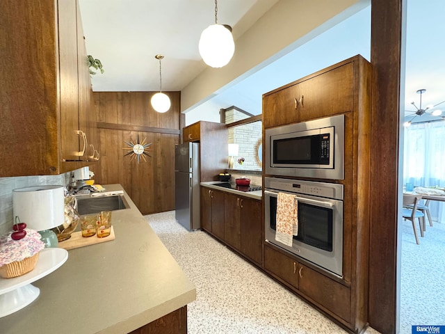 5941 Margo Dr, Lincoln, NE 68510 - kitchen with appliances with stainless steel finishes, a sink, light countertops, wooden walls, and dark aggregate flooring