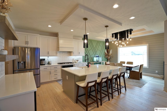 11602 S 116th St, Papillion, NE 68046 - kitchen featuring appliances with stainless steel finishes, wall chimney range hood, white cabinets, light wood-type flooring, and decorative backsplash