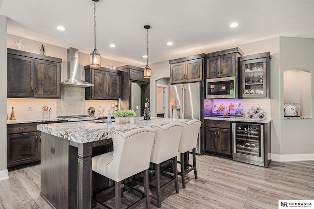 10011 S 184th St, Omaha, NE 68136 - kitchen featuring wall chimney range hood, stainless steel appliances, beverage cooler, arched walkways, and decorative backsplash