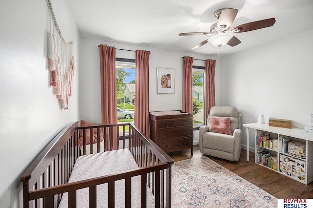 21808 Hilltop Ave, Gretna, NE 68028 - bedroom with multiple windows, wood finished floors, a crib, and ceiling fan