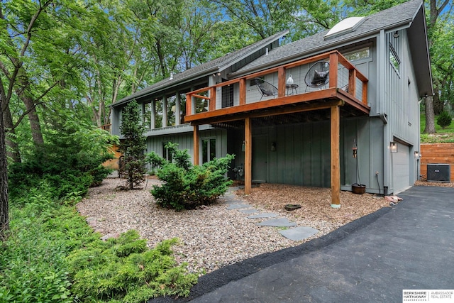 1606 Camp Gifford Rd, Bellevue, NE 68005 - view of front of property with central AC unit, an attached garage, a shingled roof, asphalt driveway, and a wooden deck
