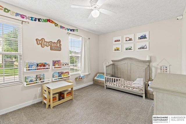 16325 Erskine St, Omaha, NE 68116 - bedroom with a crib, a textured ceiling, carpet floors, baseboards, and a ceiling fan