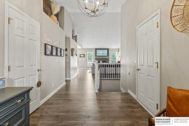 16325 Erskine St, Omaha, NE 68116 - entryway with a chandelier, dark wood-type flooring, a fireplace, a textured ceiling, and baseboards