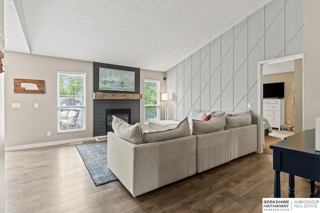 16325 Erskine St, Omaha, NE 68116 - living area featuring a textured ceiling, dark wood-type flooring, a large fireplace, and baseboards