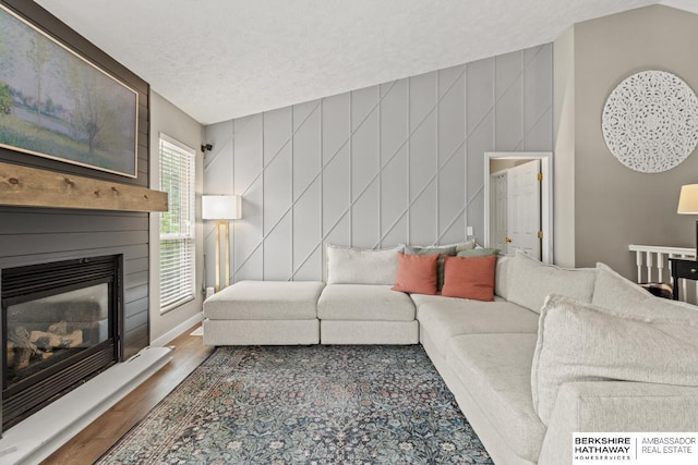 16325 Erskine St, Omaha, NE 68116 - living area featuring wood finished floors, a glass covered fireplace, a decorative wall, and a textured ceiling