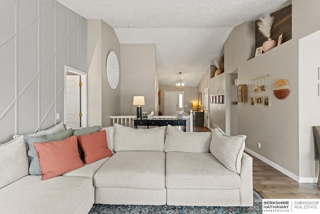 16325 Erskine St, Omaha, NE 68116 - living room with wood finished floors, vaulted ceiling, a chandelier, and baseboards