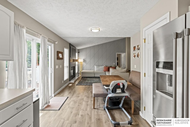 16325 Erskine St, Omaha, NE 68116 - living area with an accent wall, light wood-style flooring, a textured ceiling, baseboards, and a glass covered fireplace
