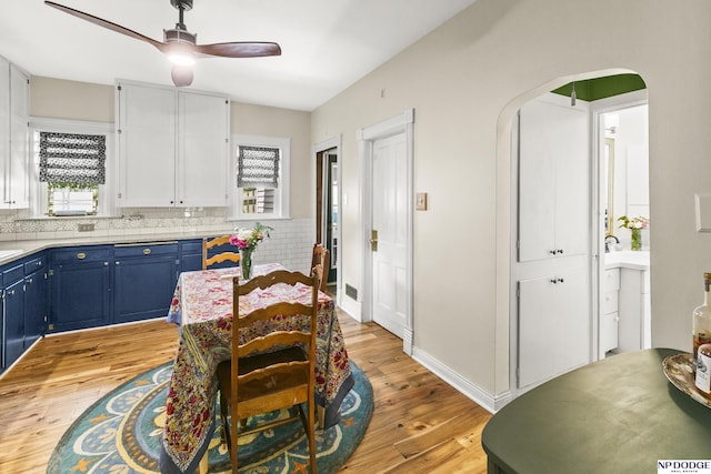 15410 Bennington Rd, Bennington, NE 68007 - kitchen with blue cabinetry, a ceiling fan, light wood-style flooring, white cabinetry, and arched walkways
