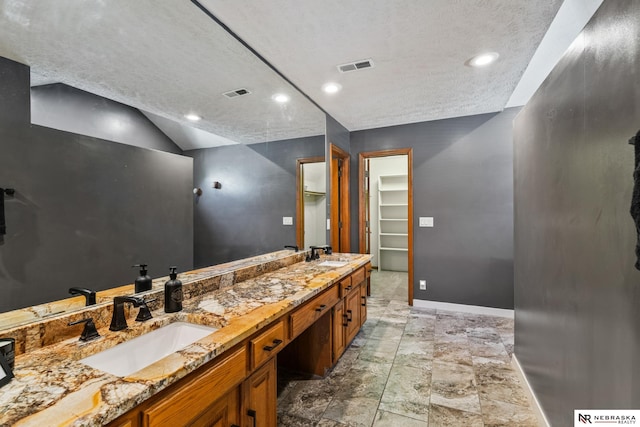 716 N 148th St, Omaha, NE 68154 - full bathroom featuring a spacious closet, double vanity, a textured ceiling, baseboards, and vaulted ceiling