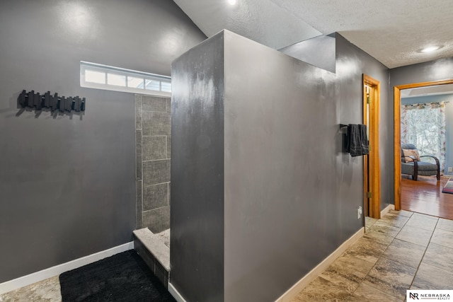 716 N 148th St, Omaha, NE 68154 - bathroom with baseboards, tiled shower, and a textured ceiling