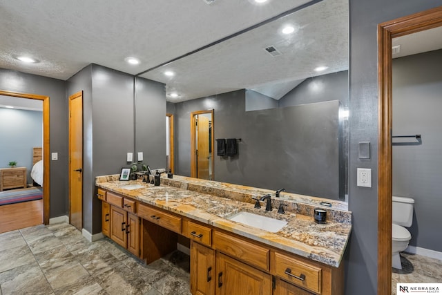 716 N 148th St, Omaha, NE 68154 - bathroom with baseboards, double vanity, toilet, ensuite bath, and a textured ceiling