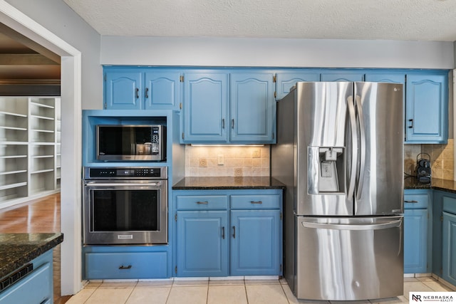 716 N 148th St, Omaha, NE 68154 - kitchen featuring appliances with stainless steel finishes, blue cabinetry, dark stone countertops, and a textured ceiling