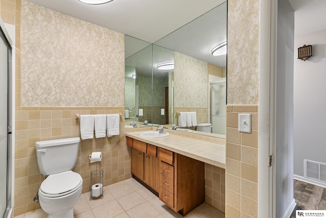 112 W Lakeshore Dr, Lincoln, NE 68528 - bathroom with tile walls, toilet, vanity, a stall shower, and wainscoting