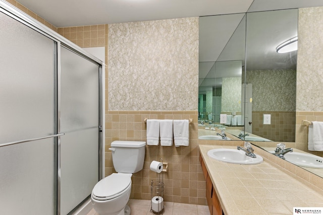 112 W Lakeshore Dr, Lincoln, NE 68528 - bathroom featuring tile walls, double vanity, toilet, a shower stall, and tile patterned flooring