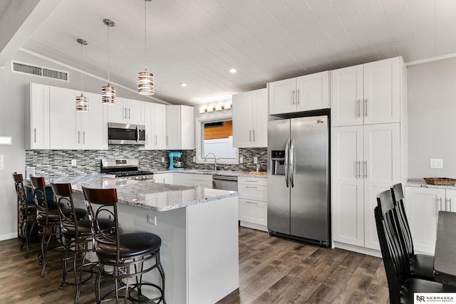 112 W Lakeshore Dr, Lincoln, NE 68528 - kitchen featuring appliances with stainless steel finishes, a peninsula, dark wood-type flooring, backsplash, and white cabinetry