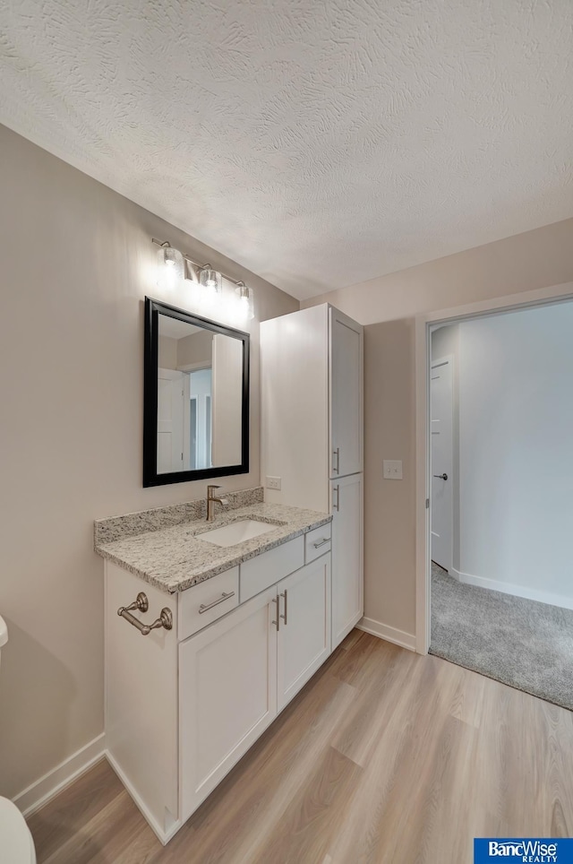 3556 Pearl Crescent Dr, Lincoln, NE 68504 - bathroom featuring wood finished floors, vanity, a textured ceiling, baseboards, and toilet
